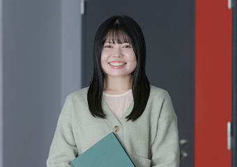 資料を持って笑顔で立つ女性のポートレート